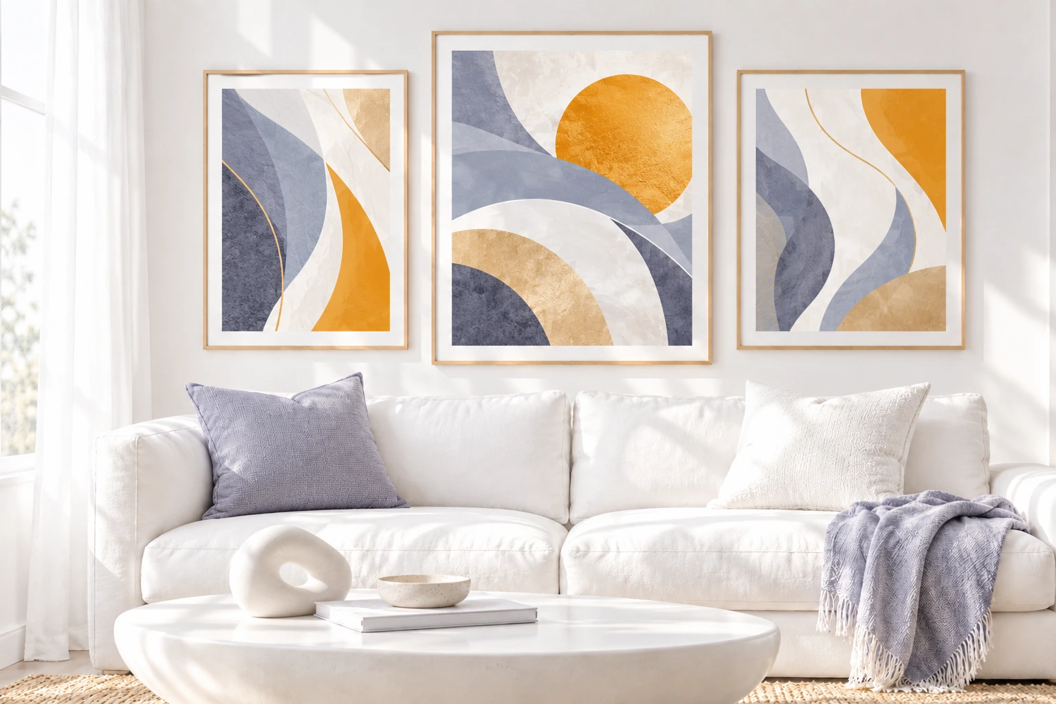 Three denim, slate and golden Clementine abstract prints above a white sofa